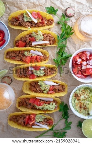 A serving of delicious Mexican tacos with ingredients on the table