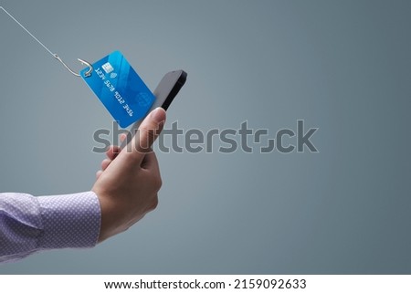 Phishing and cyber security: hacker stealing a user's credit card information on a smartphone Royalty-Free Stock Photo #2159092633