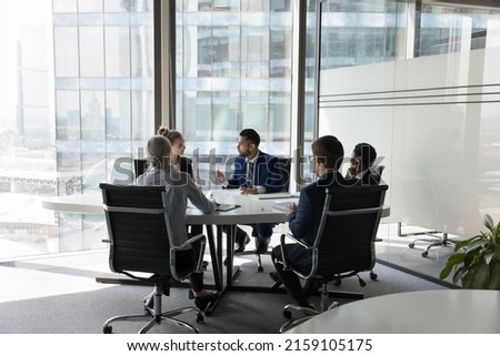 Serious team of professionals, five multi ethnic business people negotiating in modern boardroom, discuss project, consider contract terms and conditions, solve business. Formal meeting event concept Royalty-Free Stock Photo #2159105175