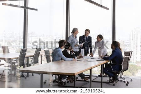 Business meeting, corporate training event, company management led by middle-aged woman concept. Group of multi racial young and older staff members take part in morning briefing in modern boardroom Royalty-Free Stock Photo #2159105241