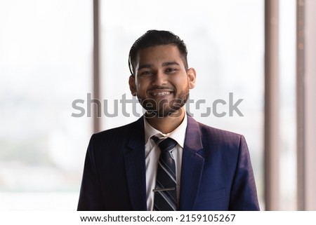 Head shot Indian businessman in formal suit pose in office smile staring at camera look proud by career growth, promotion, get hired in company position. Project leader, executive CEO portrait concept