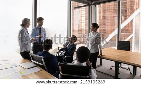 Six multi ethnic diverse business partners brainstorming, think over collaborative task, share opinion, listen to team leader, take part at group meeting in modern city office. Briefing event concept Royalty-Free Stock Photo #2159105269