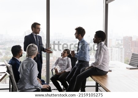 Team leader lead corporate meeting with multi ethnic teammates in modern office boardroom. Group of employees, staff members take part in morning briefing with company boss. Business meeting concept Royalty-Free Stock Photo #2159105275