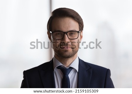 Head shot handsome millennial successful businessman in formal elegant suit and tie pose in office staring at camera looks confident. Leadership, banker, advisor or executive manager portrait concept
