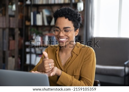 African woman teach learner via video call on laptop sit at desk show symbols with hands use gestures at remote lesson of sign language. Online speech therapist work, deaf-mute make videocall concept Royalty-Free Stock Photo #2159105359