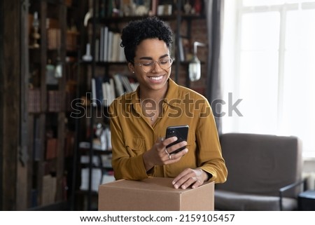 African woman client of easy trusted e-services online shipping, make order, use cellphone typing to courier, prepare parcel box for sending to friend abroad use reliable company of delivery services Royalty-Free Stock Photo #2159105457