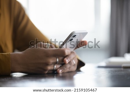 Close up cropped view African female hands holding smartphone seated at table, spend time use e-date services for singles, mobile app usage, young gen and modern wireless tech, gadget overuse concept Royalty-Free Stock Photo #2159105467