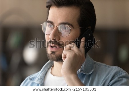 Serious talk. Concentrated young casual businessman in glasses hold smartphone to ear make answer business call contact client. Confident male expert consult customer by phone on professional matter Royalty-Free Stock Photo #2159105501