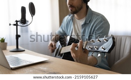 Digital audio production. Close up of young man play guitar use microphone pop filter and application software for recording music on laptop. Millennial guy musician work at home sound record studio