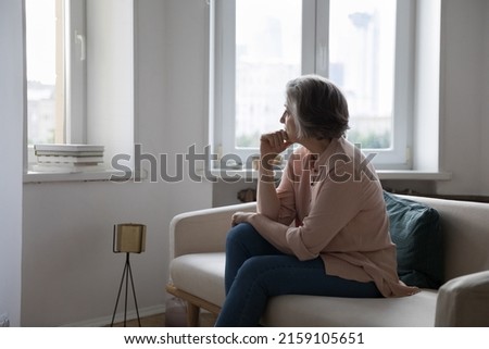 Sad lonely mature grey haired lady looking at window away, thinking over health problems, loneliness, bad news, loss, suffering from apathy, mourning depression. Frustrated middle aged woman at home Royalty-Free Stock Photo #2159105651