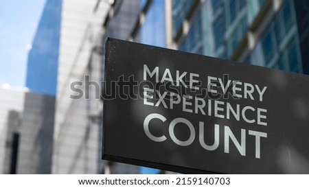 Make every experience count on a black city-center sign in front of a modern office building	