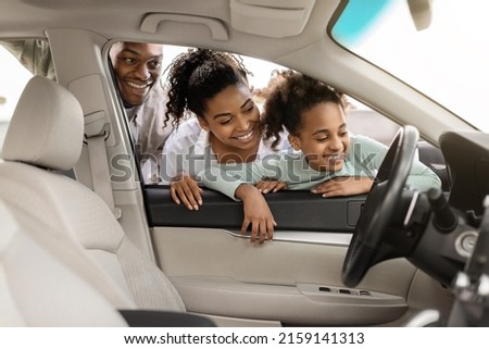 Cheerful Black Family Of Three Buying New Car, Looking Through Window At Auto Interior Choosing Luxury Automobile In Dealership. Vehicle Rent And Purchase Concept Royalty-Free Stock Photo #2159141313