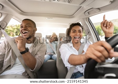 Cheerful Black Family Singing Riding New Car Having Fun Enjoying Road Trip On Vacation. Parents And Daughter Traveling By Automobile In Summer. Selective Focus Royalty-Free Stock Photo #2159141345