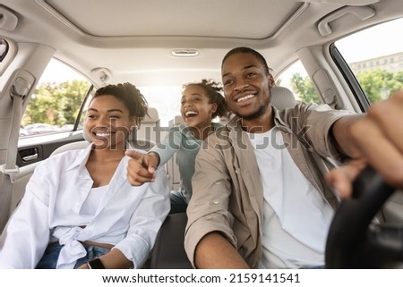 Auto Purchase. Joyful Black Family Having Road Trip Sitting In New Car Enjoying Summer Weekend Together. Parents And Daughter Riding Across City Traveling By Automobile. Selective Focus Royalty-Free Stock Photo #2159141541