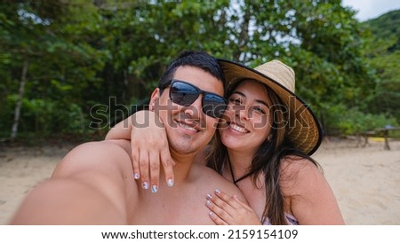 beautiful latin couple taking a selfie on the beach woman with typical brazilian cap chileand and brazilian