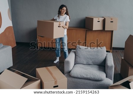 Hispanic girl is holding box and leaving apartment. Happy young woman relocates alone. Single lady moves. Real estate purchase, mortgage, delivery service ordering concept. Royalty-Free Stock Photo #2159154263