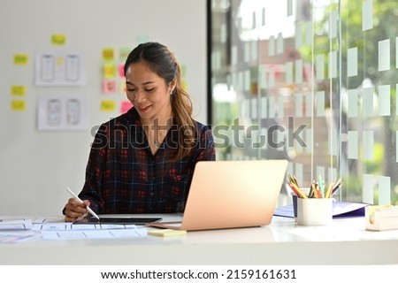 Young Asian designer working with laptop computer in creative office, Developing a New app design and User interface in a digital graphics editing software.