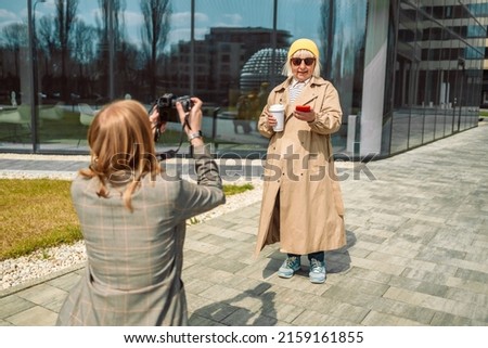 Professional female photographer take photo for women at business centre at morning time, private photo session and paparazzi.