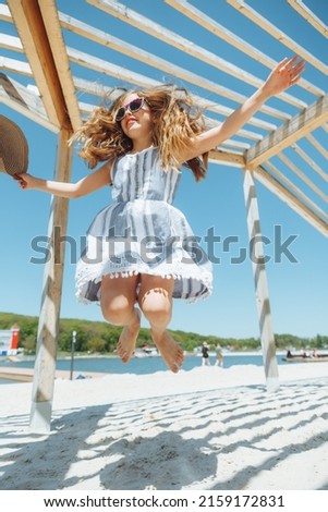 little girl jumping on the beach on the shore of the city beach in the summer holidays