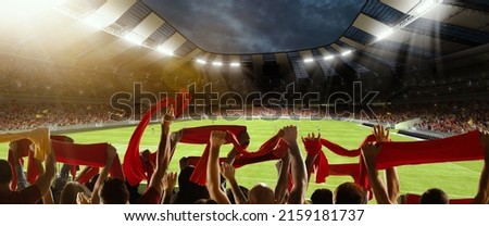 Win, victory of favourite team. Back view of football, soccer fans cheering their team with red scarfs at crowded stadium at evening time. Concept of sport, cup, world, event, competition Royalty-Free Stock Photo #2159181737