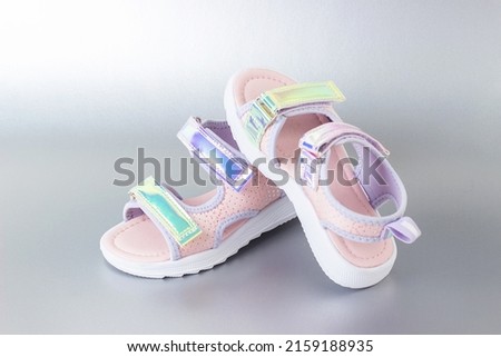 Stylish holographic sandals for kids on grey background. Shiny fashion summer shoes.