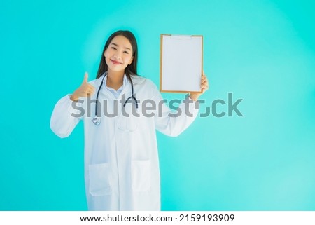 Portrait beautiful young asian doctor woman with empty card billboard banner on blue isolated background