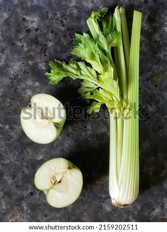 Fresh slice of green apple and celery stalk on a black concrete background. Spring green vegetables and fruit. Salad ingredients.