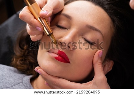 Young woman making lips tatouage in a dressing makeup room. Lips tatouage process .Woman making lips blushing. Make-up artist in beauty studio doing makeup for beautiful girl. Making mua. Royalty-Free Stock Photo #2159204095