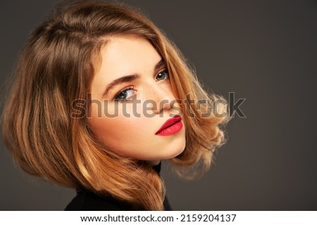 Closeup portrait of an young adult girl with medium length hair.  Photo of a fashion model posing at studio. Pretty young woman with red lips looking at camera. Beauty portrait. 