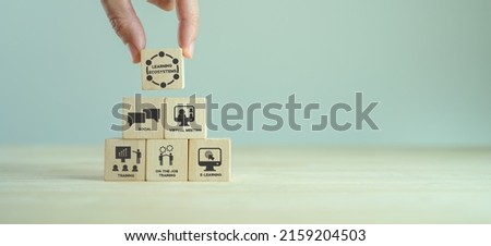 Learning ecosystems concept. Building a blended learning ecosystems. Necessary for digital evolution and transformation.  Holding wooden cubes with text"Learning Ecosystems"on grey background. Royalty-Free Stock Photo #2159204503