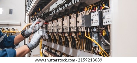 Electricity and electrical maintenance service, Engineer hand holding AC voltmeter checking electric current voltage at circuit breaker terminal and cable wiring main power distribution board. Royalty-Free Stock Photo #2159213089