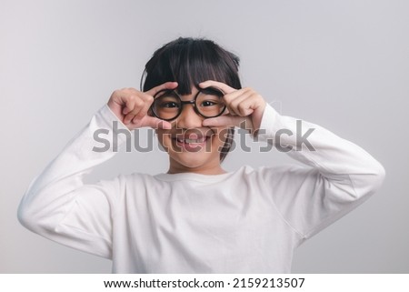 education, school and vision concept - smiling cute little girl in black glasses Royalty-Free Stock Photo #2159213507