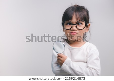 Little girl child holding a magnifying glass on white background