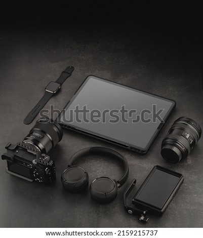 Devices mockup template. Video accessories on a dark structural background. Tablet, headphones, phone, lens, video camera and watch