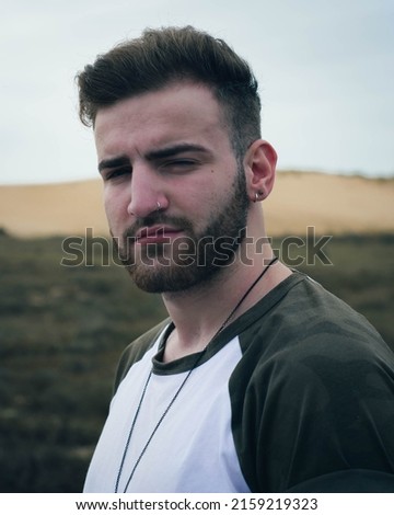 A Portrait of a caucasian young boy with a military printed t-shirt with a  dark background