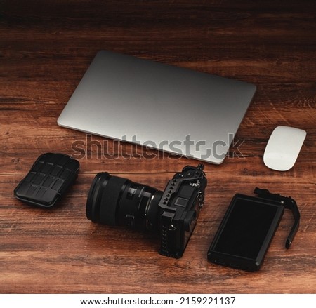 Workspace mockup template  on wood structural background. Videographer workplace with camera, laptop, playback monitor, memory card holder and  lens.