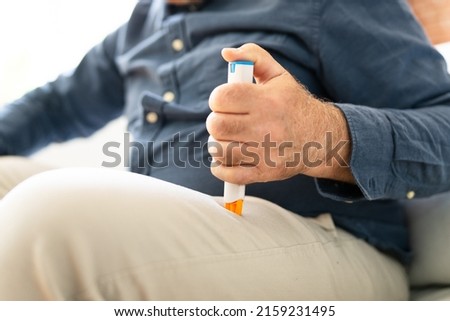 Man Injecting Epinephrine Using Auto-injector Syringe As An Emergency Treatment For Allergic Reaction Royalty-Free Stock Photo #2159231495