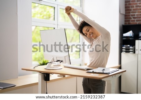 Worker Stretch Exercise At Stand Desk In Office Royalty-Free Stock Photo #2159232387