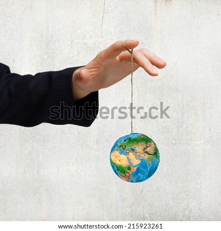 Close up of human hand holding Earth planet on rope. Elements of this image are furnished by NASA