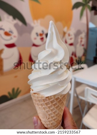 White ice cream mix using a cone held by a man's hand and the background is blurred