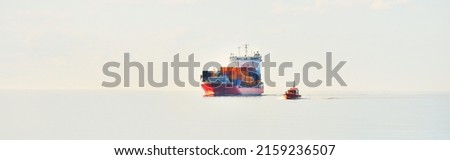Large cargo container ship being led by the pilot boat. Piloting service. Unknown waters. Global communications, logistics, industry, freight transportation, nautical vessel, nautical route, port Royalty-Free Stock Photo #2159236507
