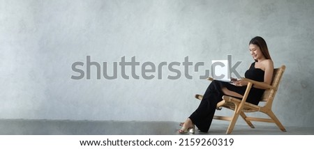 Horizontal photo banner for website header design, Attractive young woman sitting on wooden chair and using laptop computer.