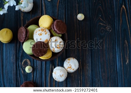 multicolored macaroon cakes on a dark wooden background