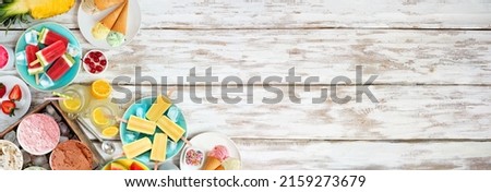 Refreshing summer foods corner border. Selection of ice cream, popsicles and fruit. Top down view over a white wood banner background. Royalty-Free Stock Photo #2159273679