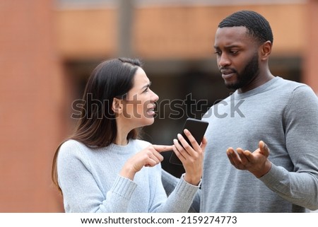 Disgusted woman asking for explanation about mobile phone text to a man in the street Royalty-Free Stock Photo #2159274773