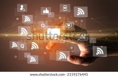 Hand pressing social media multimedia application screen with media icons on futuristic concept