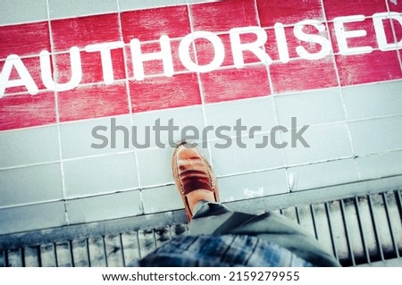 A view of a foot stepping on a floor marked with "Authorised" inscription with red