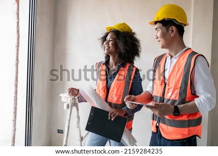 Two civil engineers man and woman inspecting  construction of house in village that they responsible for outdoors for construction of residential houses to be in accordance with standards and strong