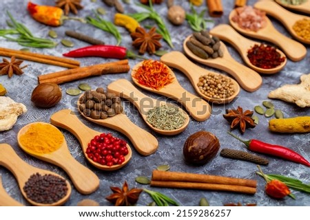 A set of spices on a gray background. Variety of spices from India. Food decoration design. Various spices, peppers and herbs close-up top view. Set of peppers, salt, herbs and spices for cooking. Royalty-Free Stock Photo #2159286257