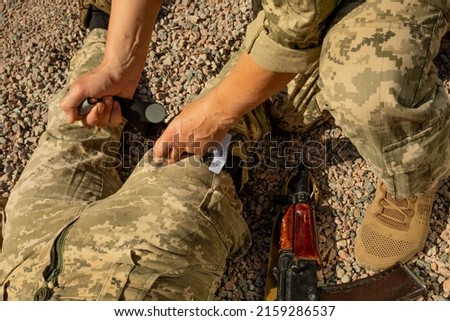 Army medics practice applying a tourniquet to the leg of a wounded soldier. Combat tactical equipment. Combat use Turnstile. The concept of military medicine. Royalty-Free Stock Photo #2159286537